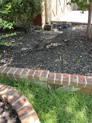 Mulch bed and brick border prep next to fresh lawn
